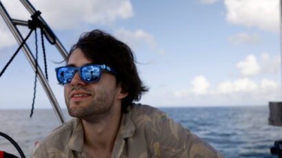 A man with brown hair and sunglasses on a boat